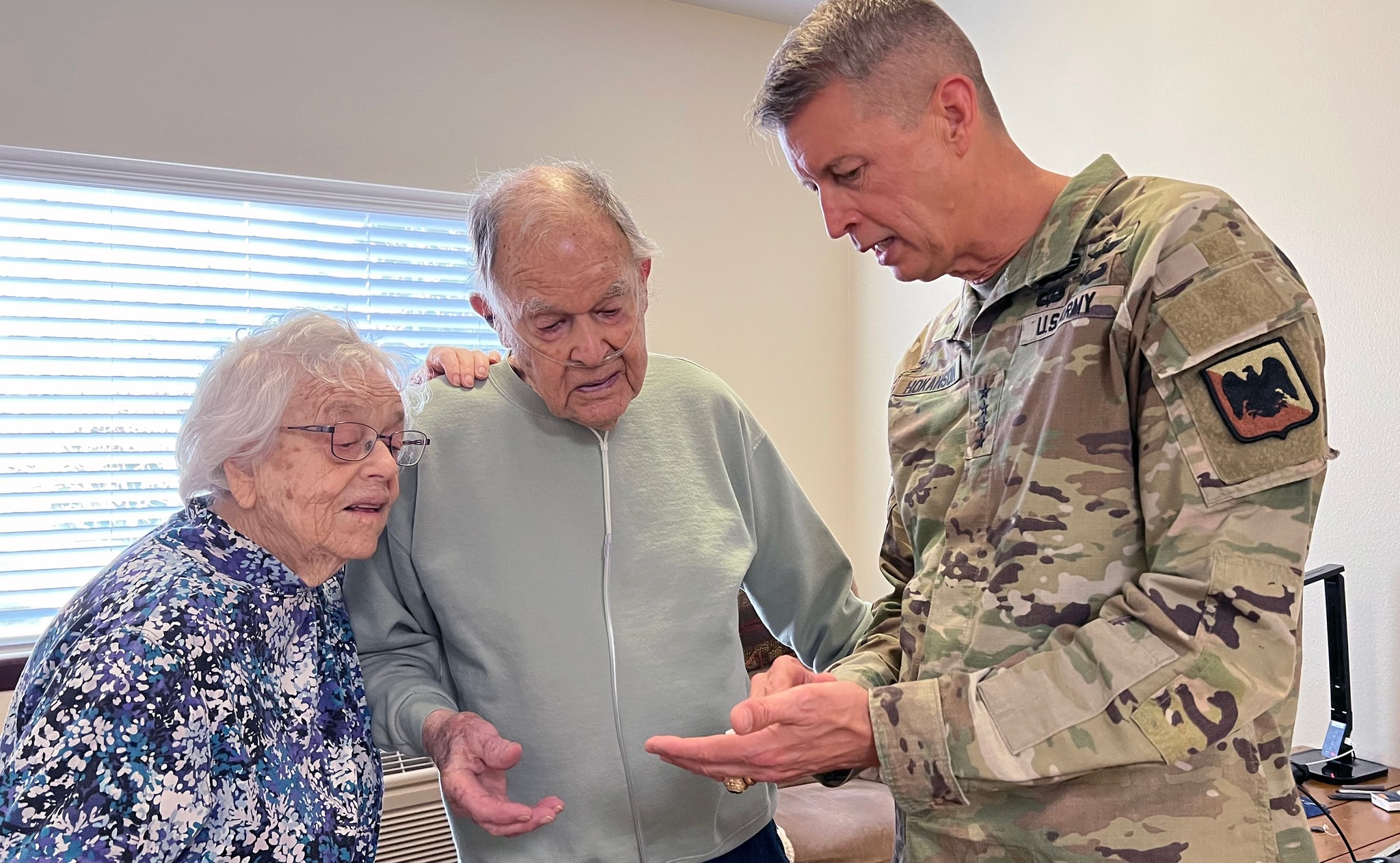 Military officer presenting a flag pin to a hospice patient and veteran in a veterans ceremony at the Hospice House in Bend, Oregon.