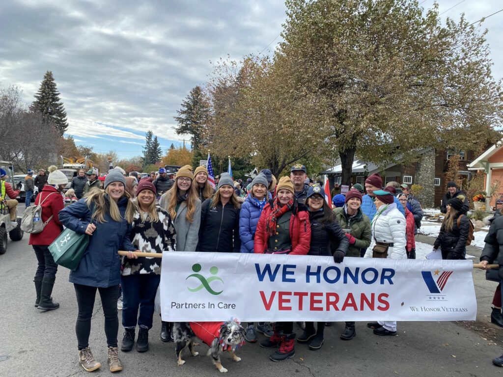 Partners in Care employees bundled in winter apparel holding a We Honor Veterans banner in a parade.