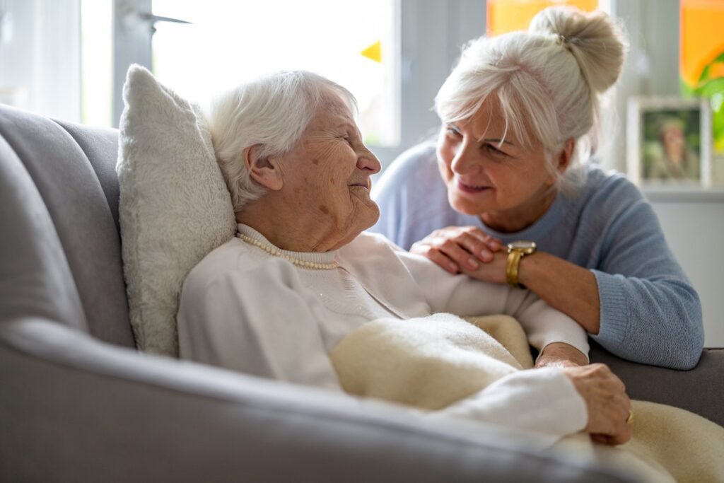 A family caregiver comforts a senior woman in hospice. 